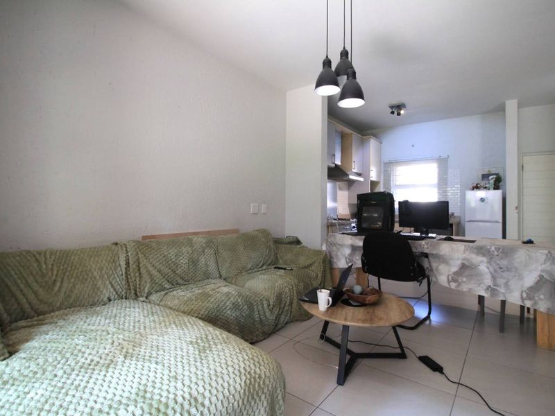 Open-plan living area featuring tiled flooring and integrated kitchen space with built-in cabinetry and appliances.