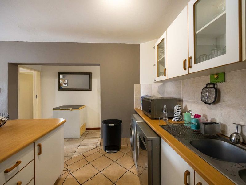 Functional kitchen featuring laminate countertops, built-in cabinetry, and tiled flooring, offering a practical layout with direct access to an adjacent utility area.
