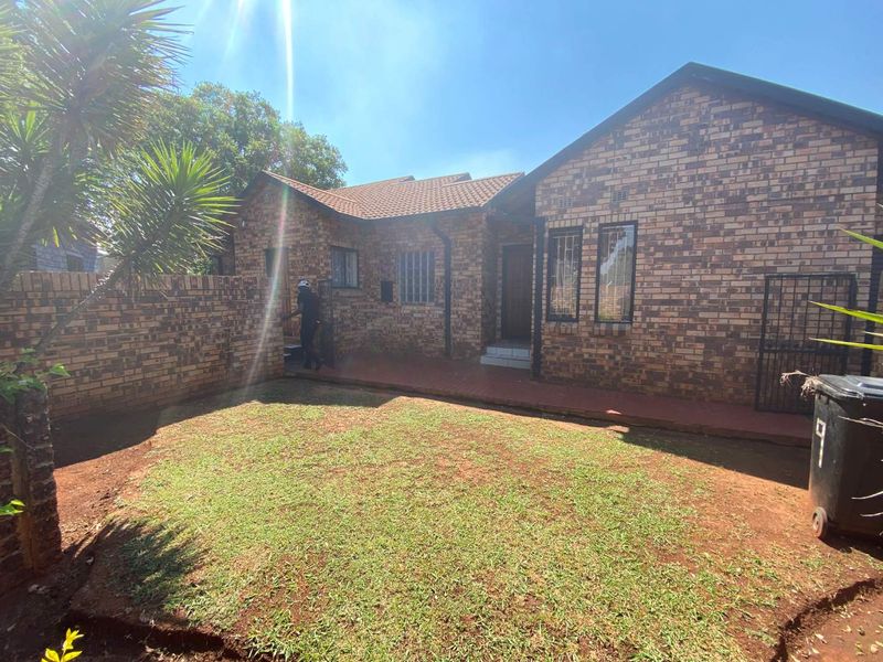 Rear view of a face brick house featuring a paved patio area and a small garden with boundary walling.