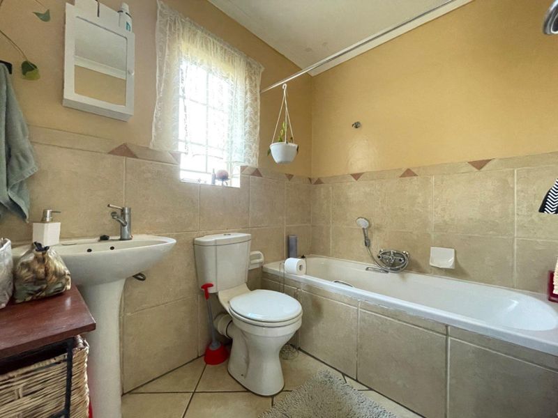 A functional bathroom featuring a pedestal basin, toilet, and bathtub with tiled finishes throughout.