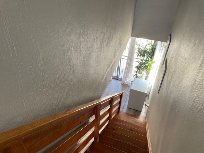 A view looking down a wooden staircase with a matching timber balustrade, leading towards a bright landing area with tiled flooring.