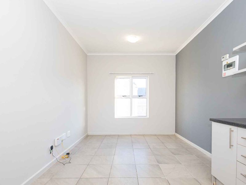 A bright, empty open-plan living and kitchen area featuring neutral walls, tiled flooring, and modern cabinetry, offering a clean canvas for personalization.