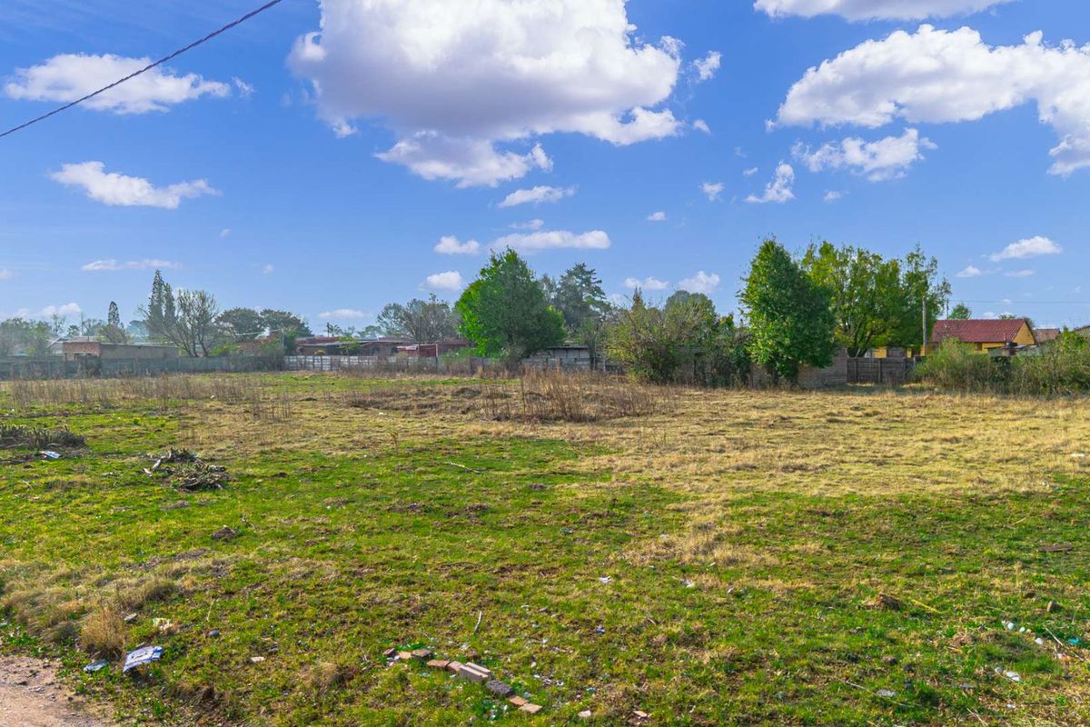 A large, undeveloped plot of land featuring open grass and perimeter fencing, suitable for future residential development.