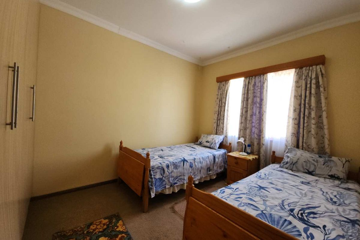 A bedroom featuring built-in cupboards and carpeted flooring, providing a functional space with natural light.