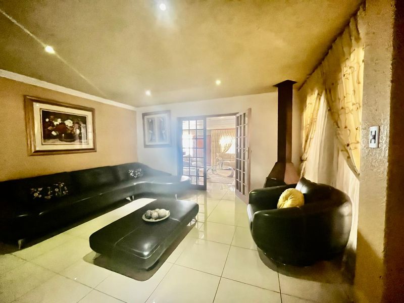 Spacious living room featuring tiled flooring, recessed lighting, and a prominent freestanding fireplace, with french doors leading to an adjacent room.