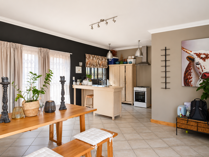 Open-plan living and kitchen area featuring ceramic tile flooring, a breakfast bar, built-in cabinetry, and an extractor fan with a neutral color palette.