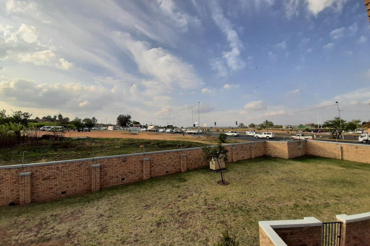 An elevated view of the property's rear garden area, featuring a perimeter brick wall and open space overlooking a nearby road.
