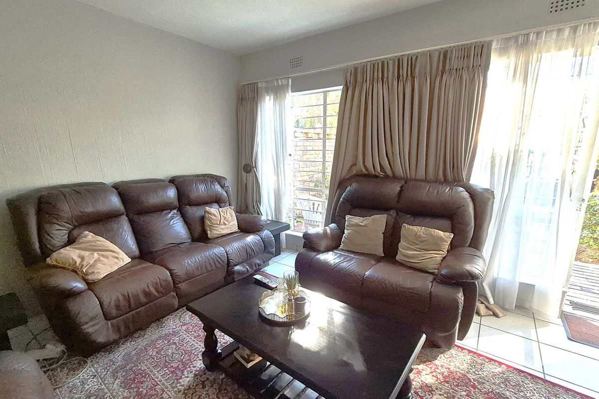 A living room featuring tiled flooring and large glass sliding doors that provide access to an outdoor area.