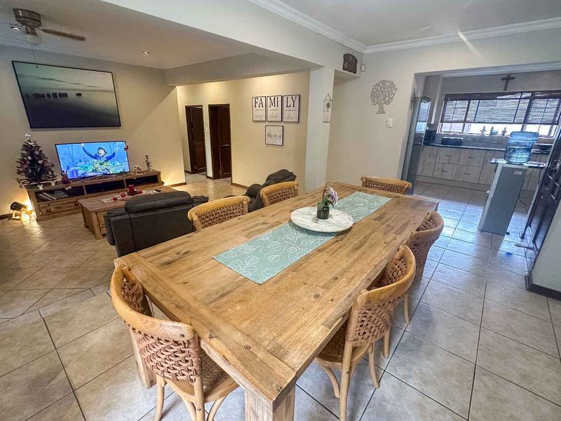 Spacious open-plan living and dining area featuring tiled flooring, recessed lighting, and a connected kitchen with built-in cabinetry.