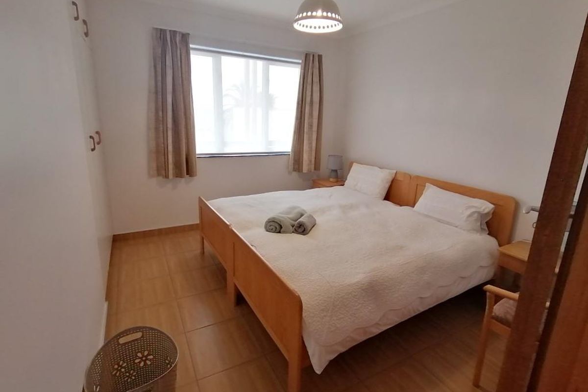 A functional bedroom featuring tiled flooring, built-in cupboards, and coving, providing a clean and simple space for rest.