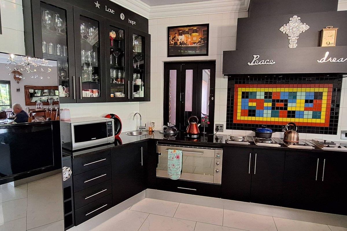 A kitchen featuring black cabinetry, granite countertops, a built-in oven, a gas hob, and a decorative tiled backsplash.