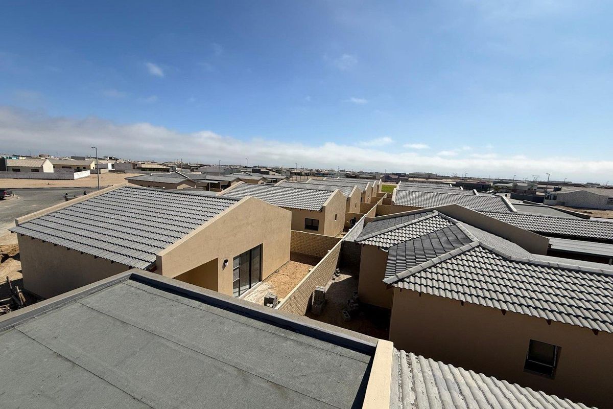 An elevated aerial view of a residential townhouse development featuring uniform tiled roofs and exterior wall finishes.