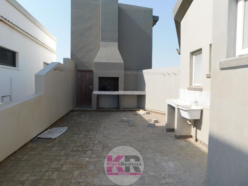 Rear courtyard featuring a built-in braai area, utility sink, and paved flooring, providing a functional outdoor space.