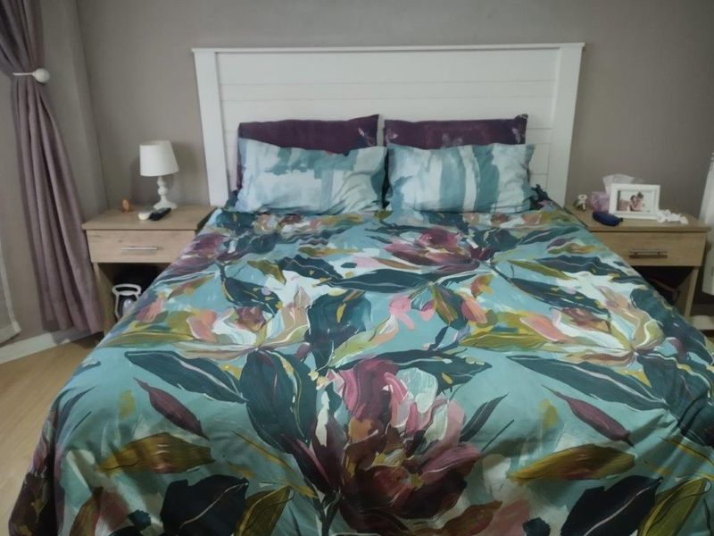 A cozy bedroom featuring laminate flooring and a built-in white headboard, providing a functional and comfortable sleeping space.