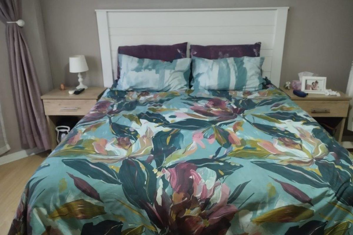 A cozy bedroom featuring laminate flooring and a built-in white headboard, providing a functional and comfortable sleeping space.