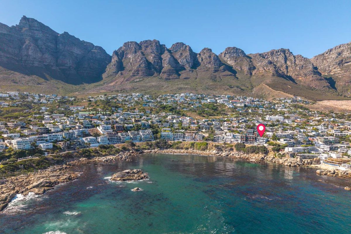 An aerial view of the coastal residential area with a location pin highlighting the property's position against the mountain backdrop.