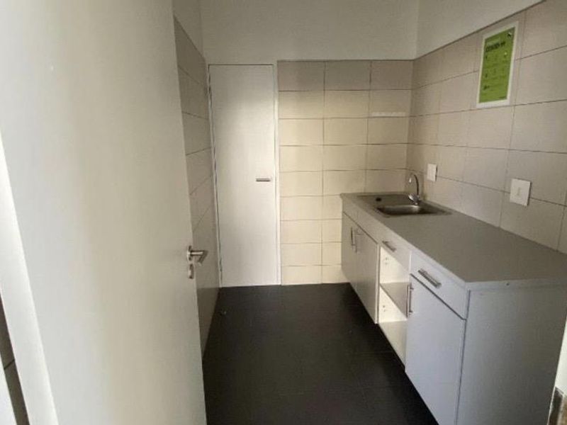 A functional scullery or utility area featuring built-in cabinetry, a stainless steel sink, and tiled finishes.