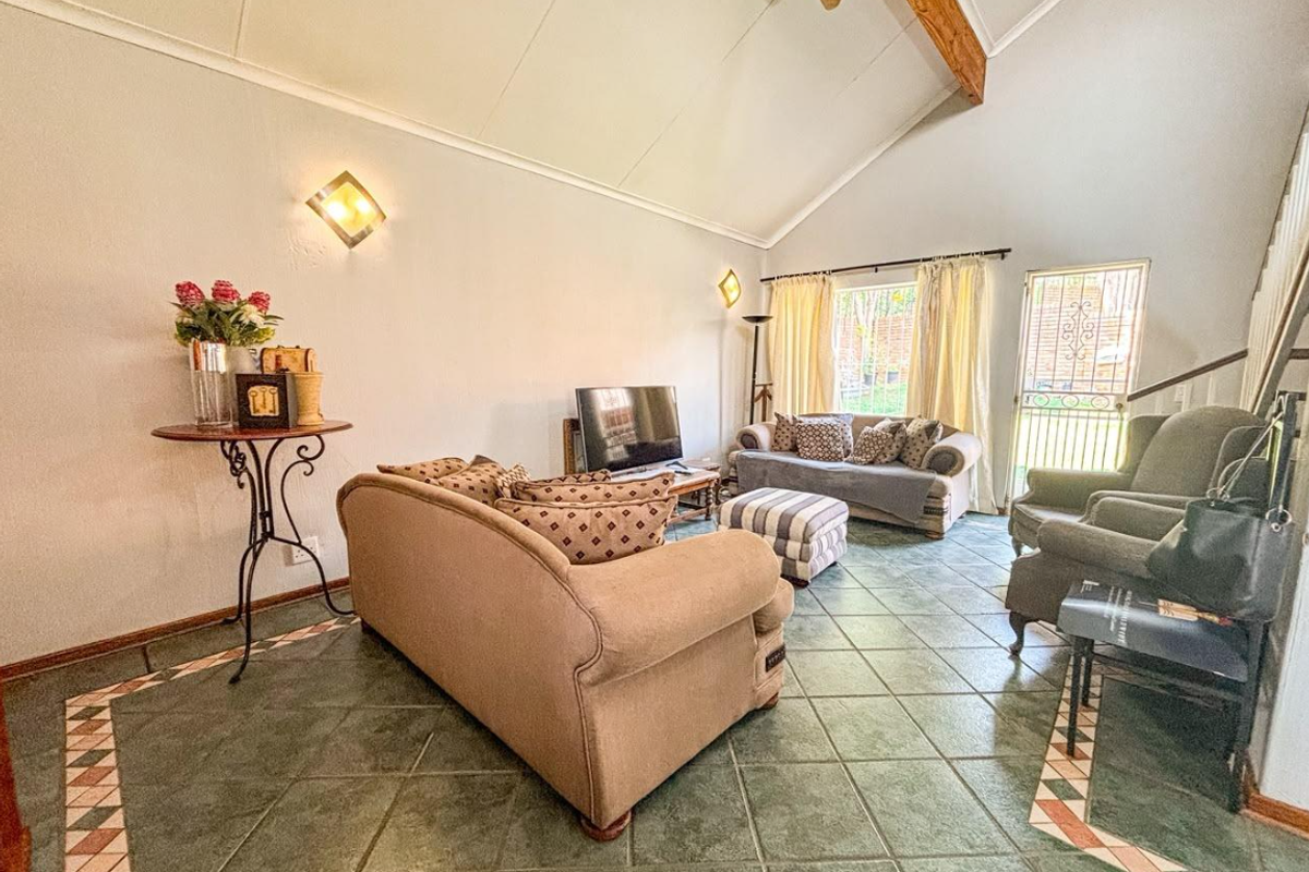 Spacious living room featuring a high vaulted ceiling with an exposed timber beam and decorative tiled flooring.