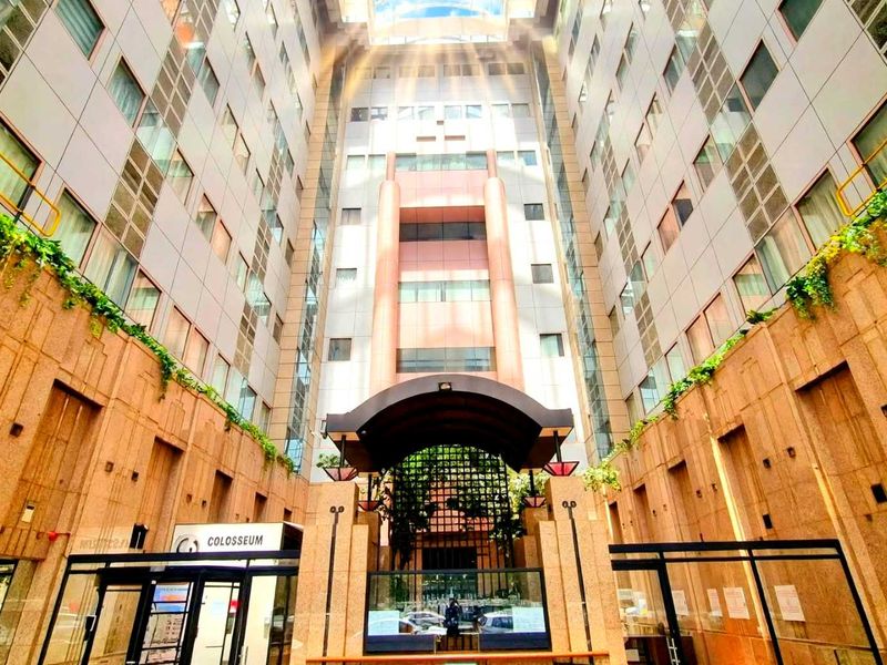 A view of the modern apartment building entrance featuring a central atrium, glass facade, and stone cladding.