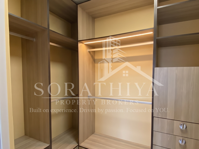 A modern walk-in wardrobe featuring custom built-in cabinetry with integrated LED lighting, hanging rails, and storage drawers.