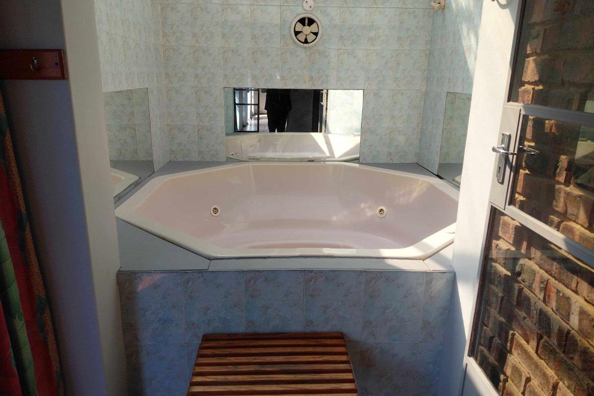 A bathroom featuring a built-in corner spa bathtub with tiled surround and integrated wall mirror.