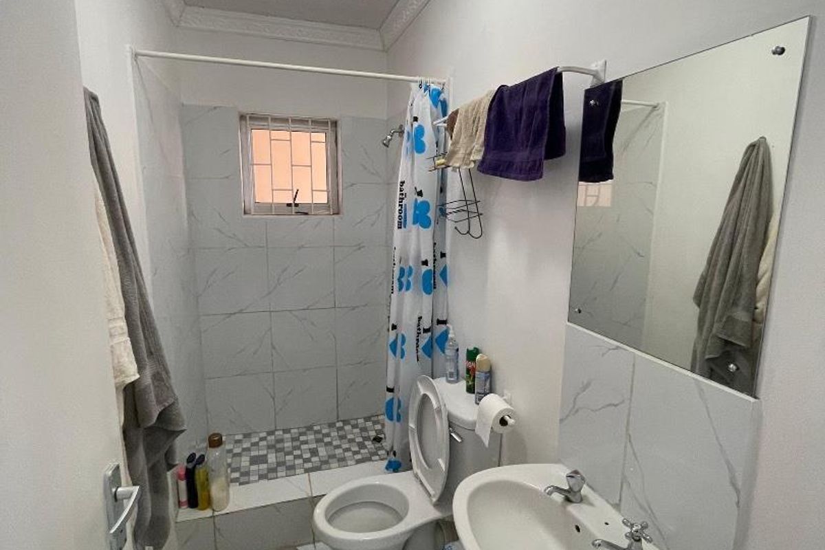 Compact bathroom featuring a walk-in shower with tiled surround, pedestal basin, and toilet, finished with marble-look floor tiles.