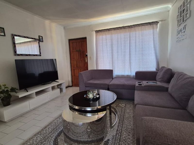 A comfortable living room featuring tiled flooring and a timber entrance door, providing a functional and welcoming space for relaxation.