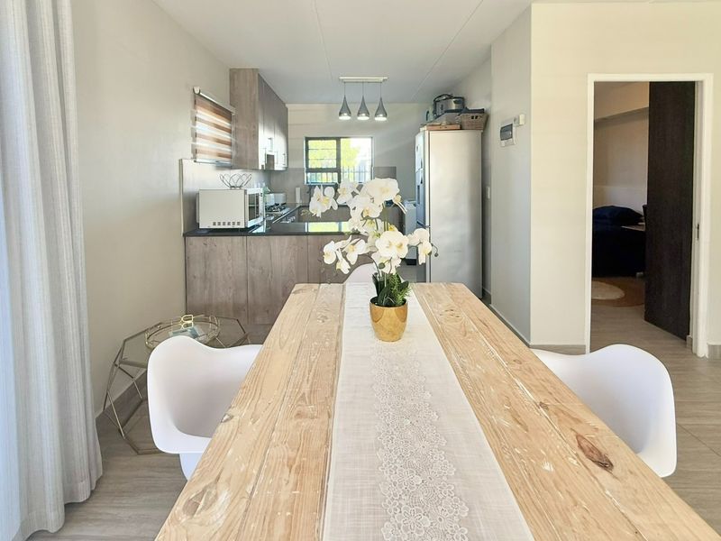 Open-plan dining and kitchen area featuring modern cabinetry, stone countertops, integrated hob, and stylish pendant lighting, creating a functional and cohesive living space.