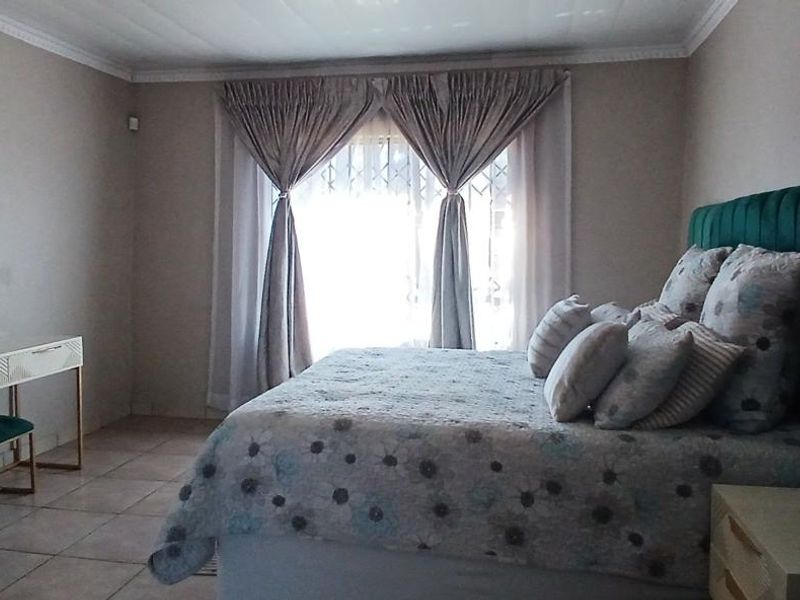 A well-maintained bedroom featuring tiled flooring, decorative cornicing, and a security gate over the window.