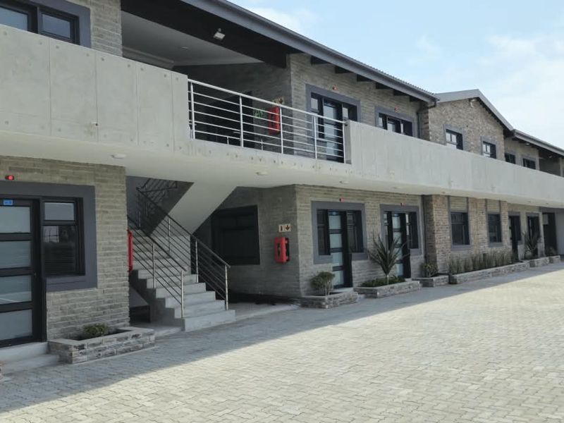 Modern apartment complex exterior featuring brick facade, concrete balconies with stainless steel railings, and a paved driveway.