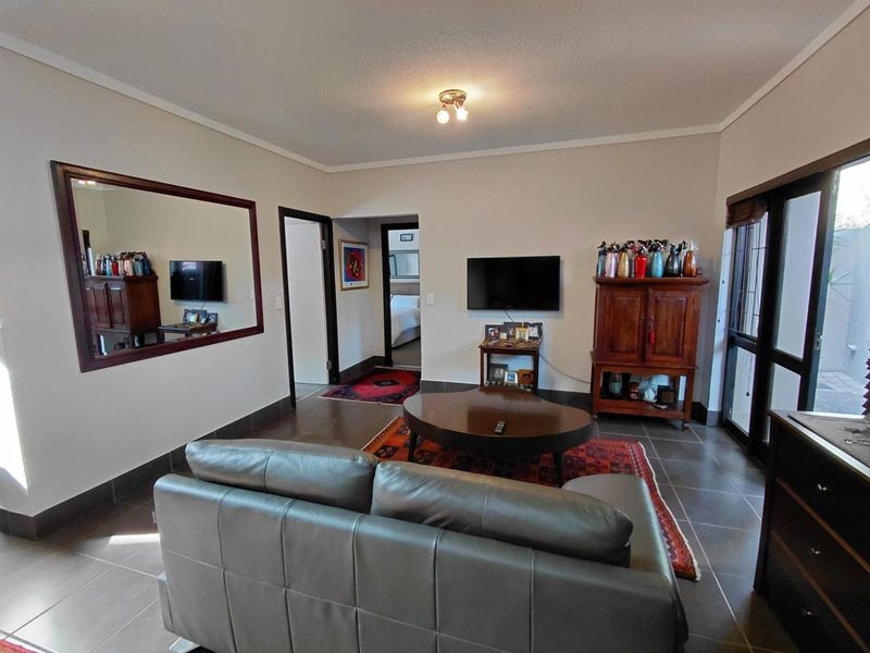 A living room featuring tiled flooring, neutral walls, and a sliding glass door providing access to the exterior.