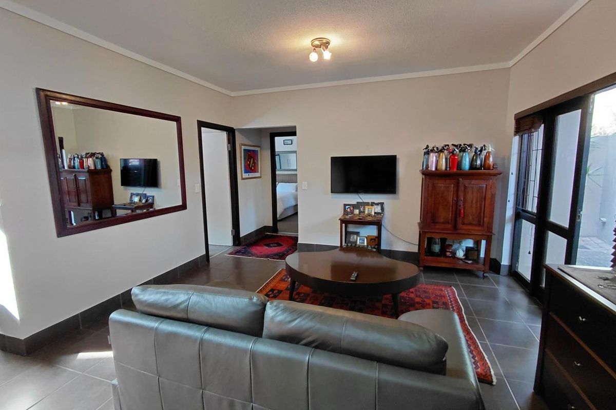A living room featuring tiled flooring, neutral walls, and a sliding glass door providing access to the exterior.