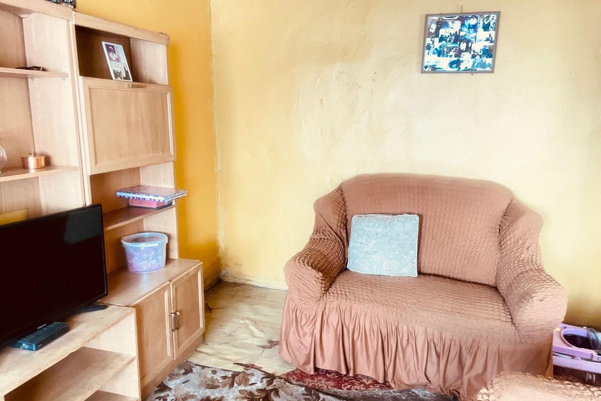 A living room area featuring yellow painted walls and visible wear on the flooring, offering potential for cosmetic updates and modernization.