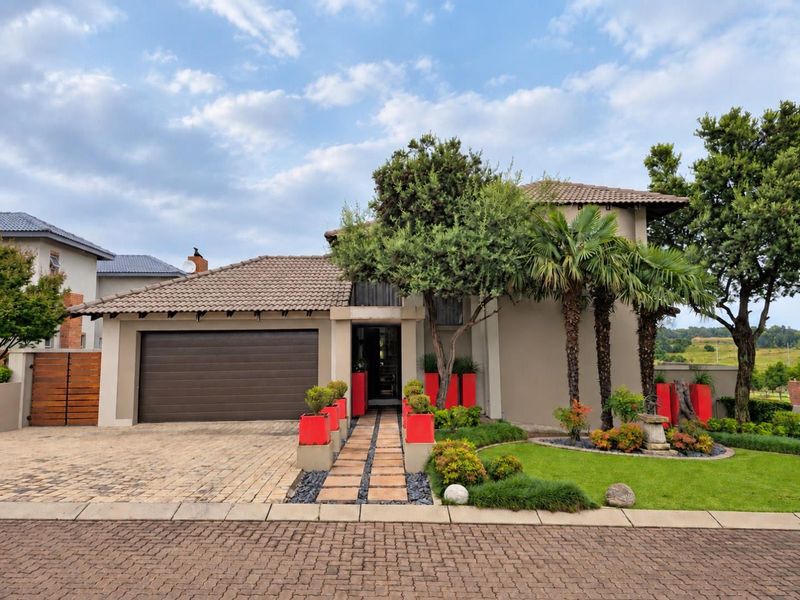 A well-maintained front elevation featuring a double garage, paved driveway, and landscaped garden with a stone pathway leading to the entrance.