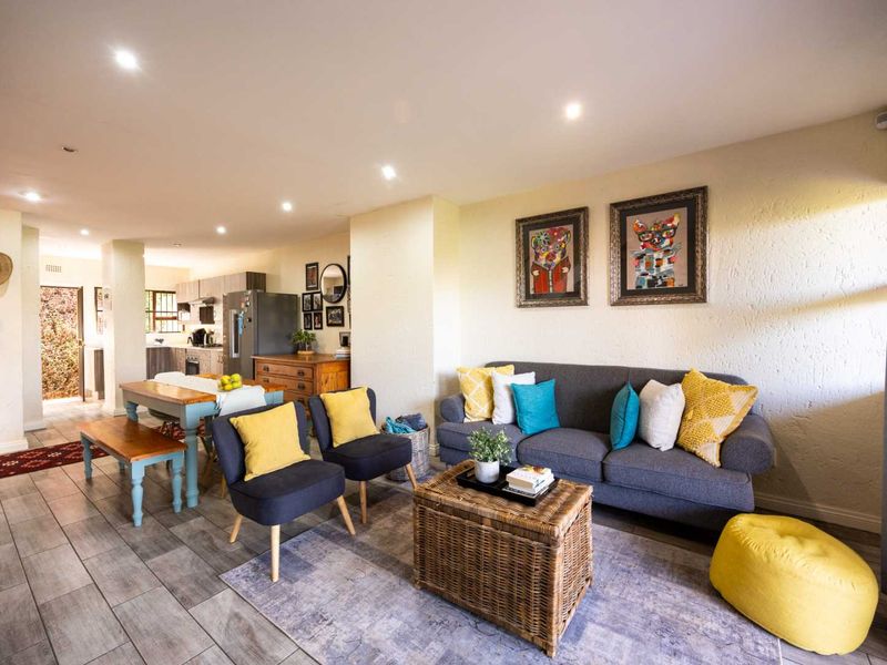 Open-plan living and dining area featuring tiled flooring, recessed downlighting, and a functional kitchen space in the background.