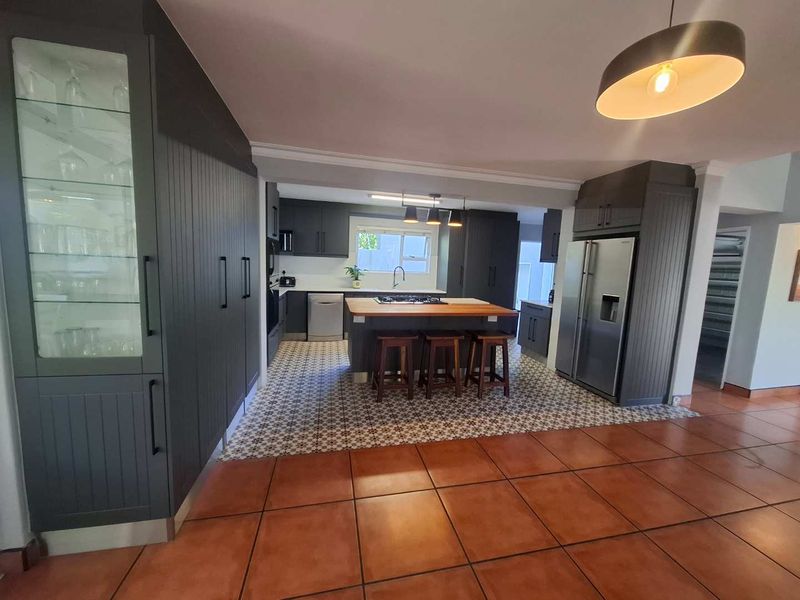 Modern kitchen featuring dark cabinetry, a central island with a wooden countertop, gas cooktop, and stylish patterned tile flooring.