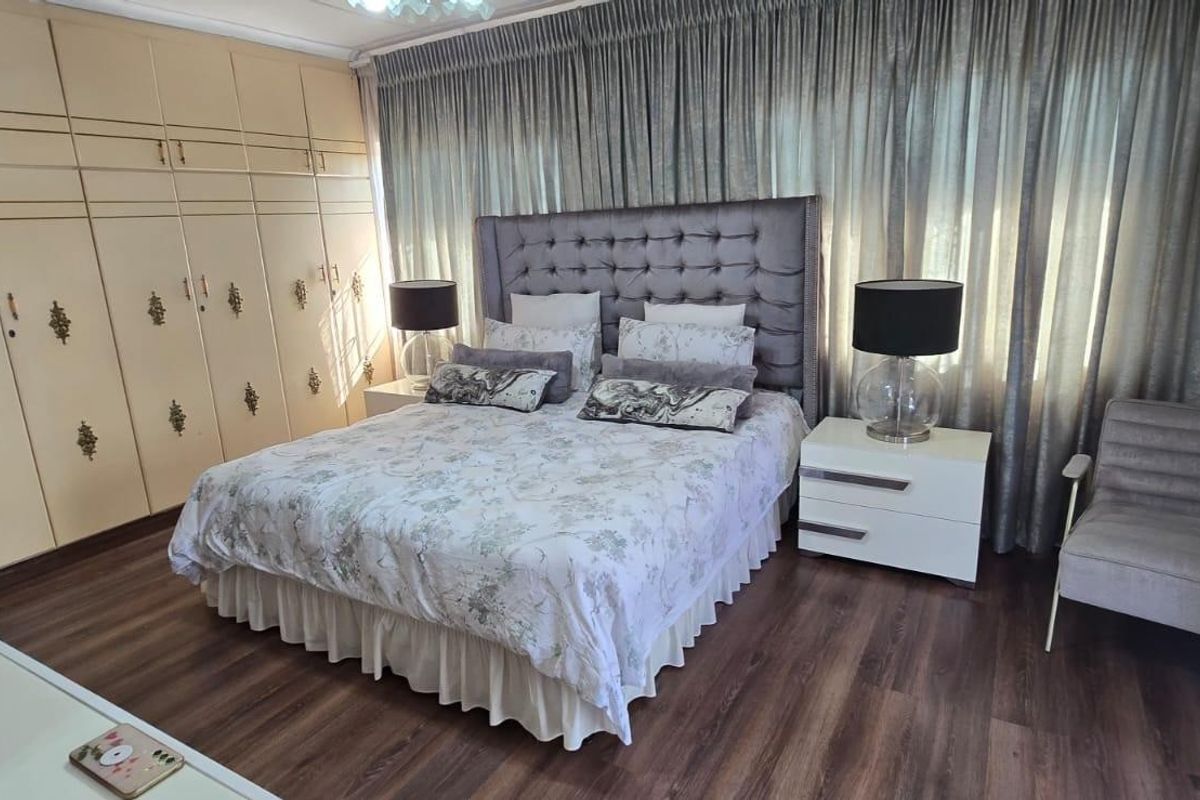 A well-maintained bedroom featuring extensive built-in cupboard storage and durable laminate flooring, providing a functional and comfortable living space.