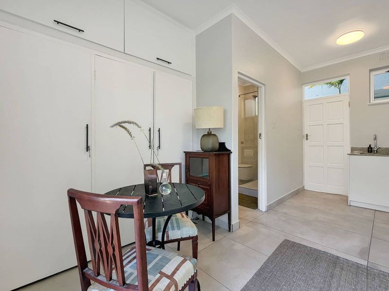 Open plan living area featuring tiled flooring, ample built-in cupboard storage, and direct access to an adjoining bathroom and kitchenette area.