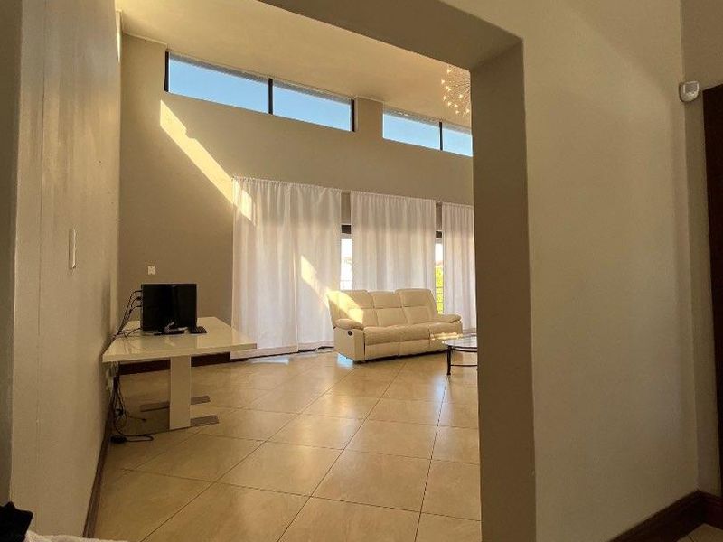Spacious living area featuring large tiled floors, high ceilings with crown molding, and clerestory windows that provide abundant natural light.