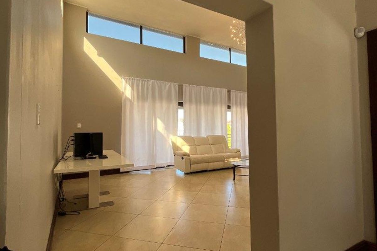 Spacious living area featuring large tiled floors, high ceilings with crown molding, and clerestory windows that provide abundant natural light.