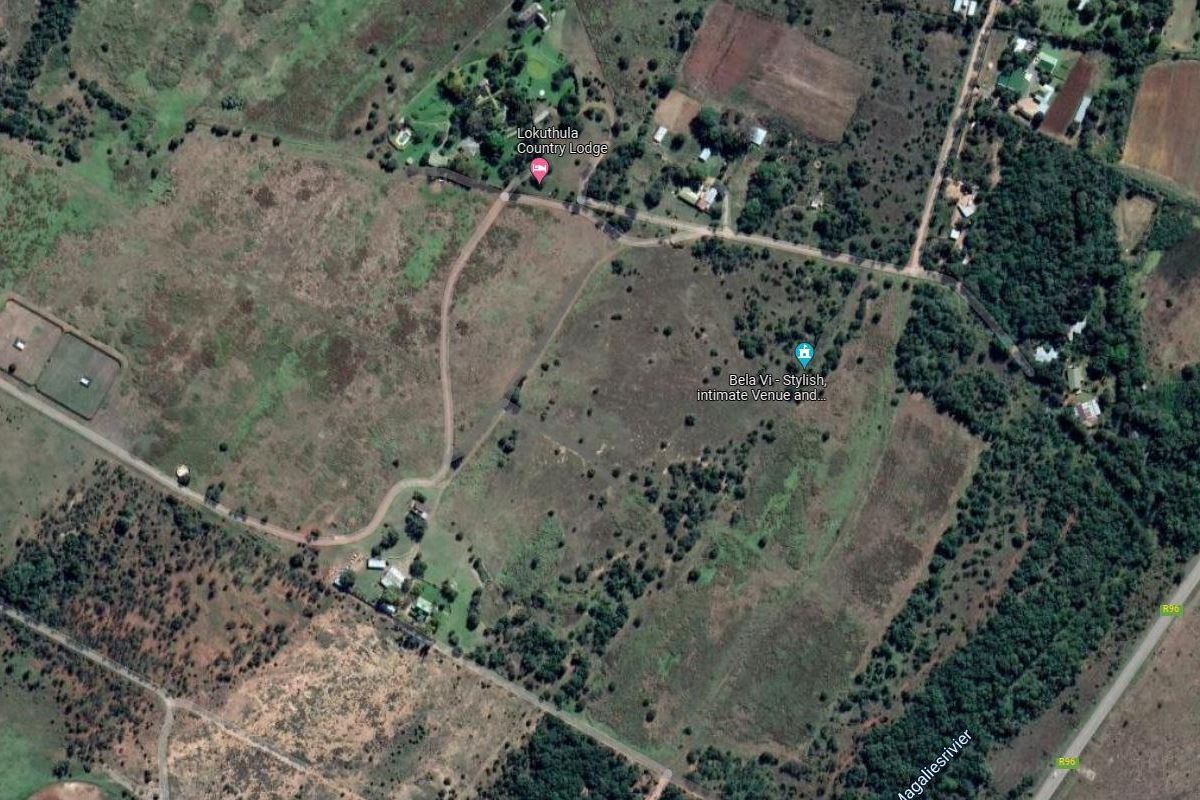 An aerial view of a large rural farm property featuring open fields, access roads, and established vegetation.