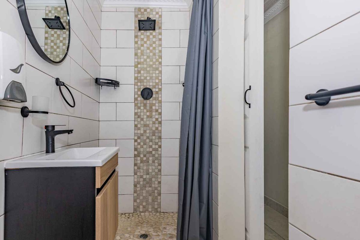 A modern bathroom featuring a walk-in shower with mosaic tile accents, a pebble-style floor, and a contemporary vanity with matte black fixtures.