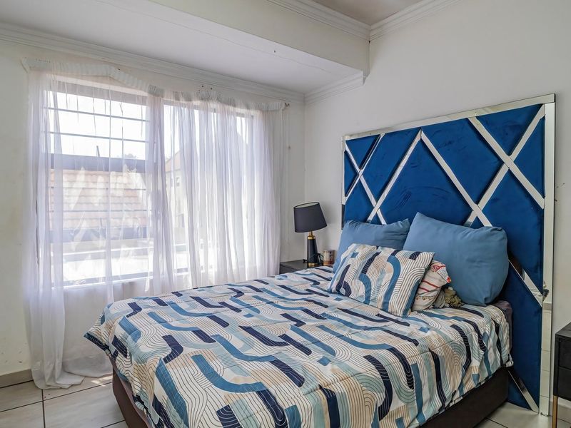 A bedroom featuring tiled flooring, crown molding, and security bars on the window, providing a functional space with potential for cosmetic updates.