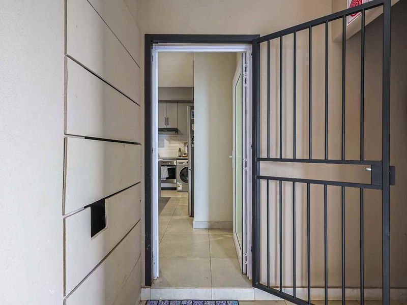 Entrance area featuring a secure metal gate, tiled flooring, and a clear view into the kitchen area.