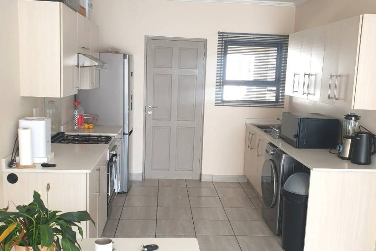 A functional kitchen featuring light-toned cabinetry, tiled flooring, and integrated appliance spaces, providing a practical layout for daily meal preparation.