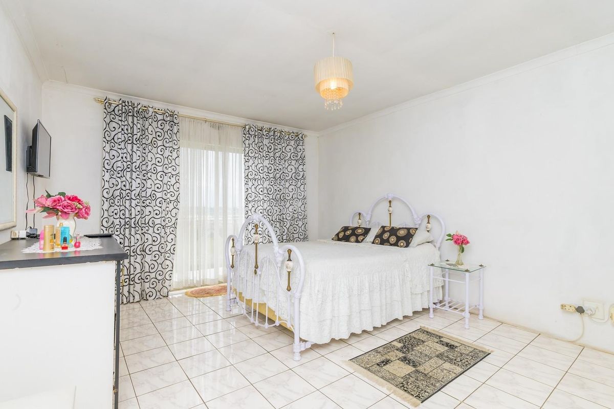 A bedroom featuring tiled flooring, a sliding glass door with curtains, and cove cornice detailing.