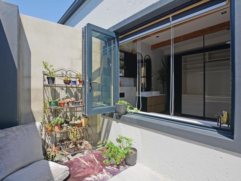 A private outdoor patio area featuring concrete flooring and a large bi-fold window opening into the interior living space.