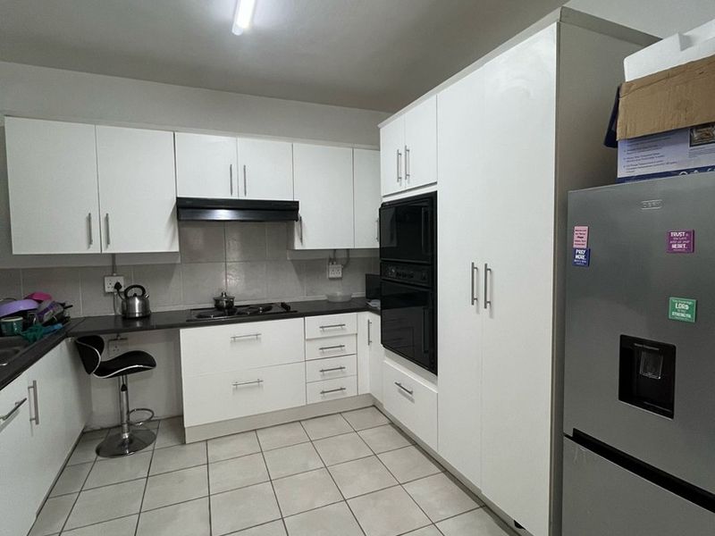 A functional kitchen featuring white built-in cabinetry, integrated oven and microwave, dark countertops, and tiled flooring with a clean, modern layout.