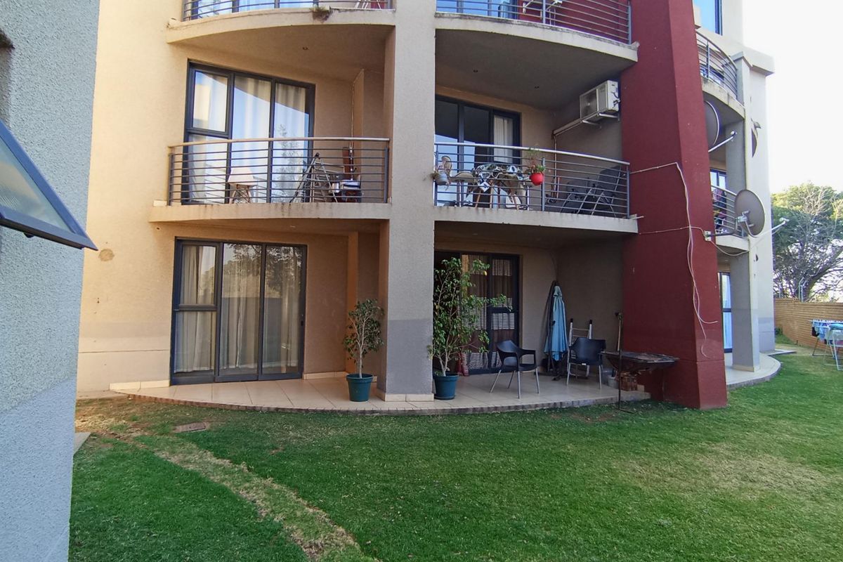 Exterior view of an apartment building featuring ground floor patio access and upper level balconies with metal railings and sliding glass doors.