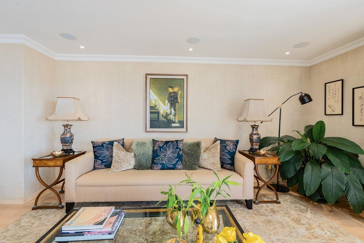A well-maintained living room featuring recessed ceiling lighting, integrated audio speakers, crown molding, and high-quality hardwood flooring.